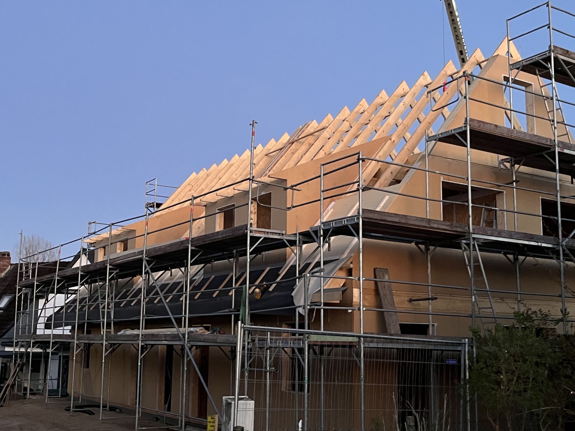 Blick durch eine moderne Dachstuhl-Holzkonstruktion aus hellem Konstruktionsholz gegen den Himmel